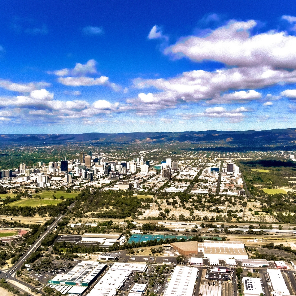 Aerial view of metropolitan Adelaide with city. There is a blue sky in the background with white clouds.