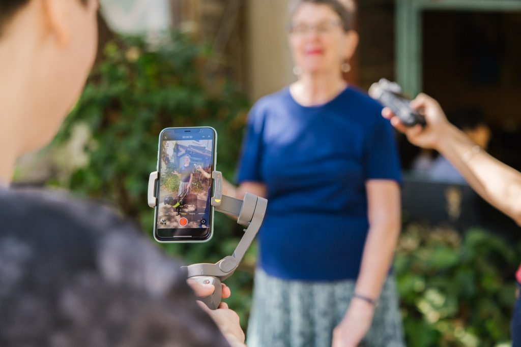 Two people are interviewing a person with disability using a mobile phone.